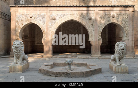 Two white marble lions statues and decorative fountain in front of three adjacent decorated stone arches at the garden of Manial Palace of Prince Moha Stock Photo