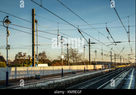 Wet winter morning looking down railway tracks, Drem Station, East Lothian, Scotland, UK, unmanned rural ScotRail train station with overhead cables Stock Photo