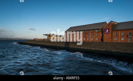Premier Inn and David Lloyd Club, Newhaven Harbour, Edinburgh, Scotland, UK, with waves lapping breakwater in Firth of Forth and blue sky Stock Photo