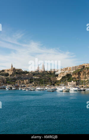The harbour and ferry terminal at Mgarr on Gozo showing buildings anda church on the town and boats in the harbour Stock Photo