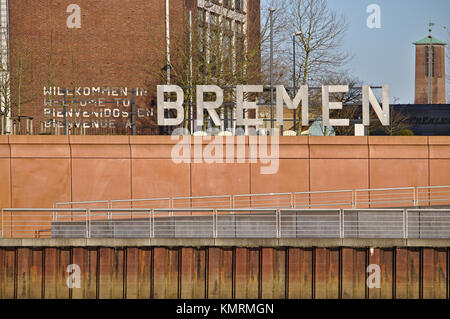 Bremen, Germany - November 25th, 2017 - Large metal sign saying Welcome to Bremen in German, English, Spanish and French mounted on brown concrete wal Stock Photo