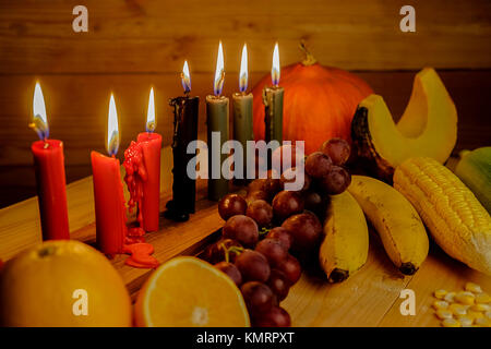 Kwanzaa holiday concept with decorate seven candles red, black and green, gift box, pumpkin,corn and fruit on wooden desk and background. Stock Photo