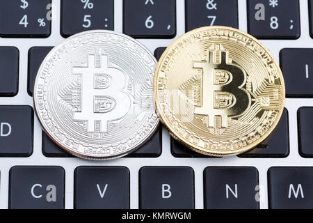 Golden and silver bitcoin coins on laptop keyboard.  Stock Photo