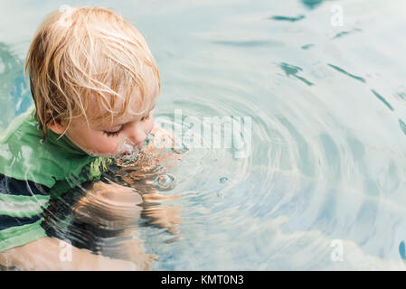 High angle view of playful boy blowing bubbles in water Stock Photo