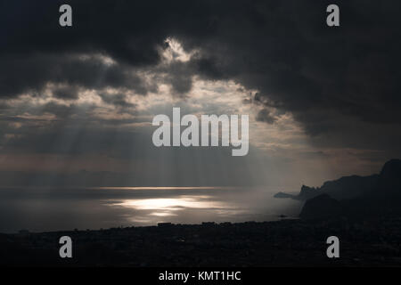 ominous clouds and the bursting rays of light over the gulf sea Stock Photo