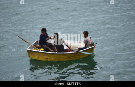 Depend on each other, three boys in a small boat on the ocean in Papua New Guinea Stock Photo