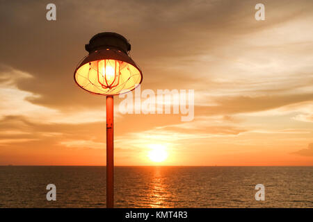 Lighting of warm lamp and lighting of sunset at sea with beautiful sky and clouds in the evening with twilight time on offshore platform.