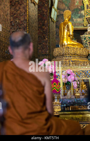 Bangkok, Thailand.  Buddhist Monk in front of Buddha at the Phra Ubosot, Wat Pho Temple Complex. Stock Photo