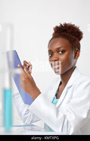 African biologist, medical student or doctor checks records, looking at the viewer. Studio shoot on neutral background Stock Photo