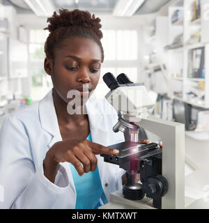 African-american female scientist, student or tech in lab coat works in modern laboratory with a microscope Stock Photo