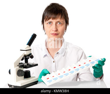 Histologist with a microscope and a tray of microscopic slides on a ...