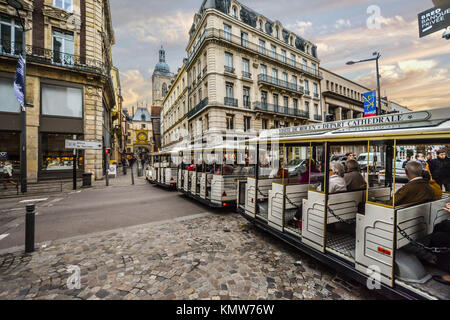 Tourists ride a tram bus with the Gros Horloge or astronomical clock in the distance in the Normandy city of Rouen France Stock Photo