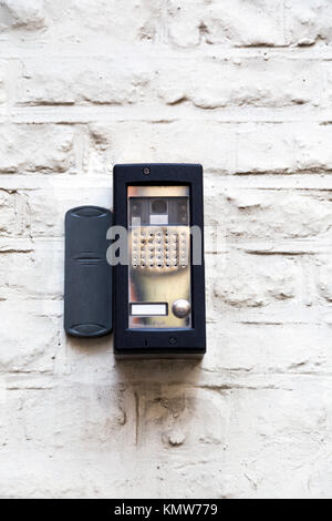 Black intercom on a white painted brick wall on the outside of a building Stock Photo