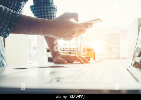 Architect or engineer using smart phone working in office on blueprint. Architects workplace Stock Photo