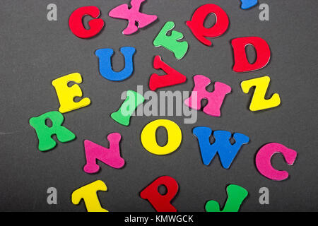 abstract background of colorful red, blue, green, yellow, and pink alphabet letters laying on gray background Stock Photo