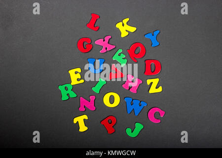 abstract background of colorful red, blue, green, yellow, and pink alphabet letters laying on gray background Stock Photo