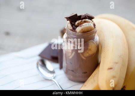 Chocolate pudding with banana in a glass jar on a textile background. Stock Photo