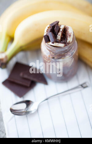 Chocolate pudding with banana in a glass jar on a textile background. Stock Photo