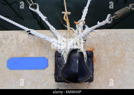 black bollard with many nautical ropes around