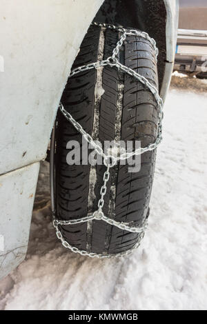 Closeup of snow chains mounted on a snowy car wheel. Stock Photo