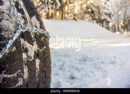 Closeup of snow chains mounted on a snowy car wheel with large copy space on the left. Stock Photo