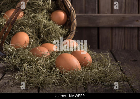 Organic brown eggs spilled from a basket on a wood surface Stock Photo