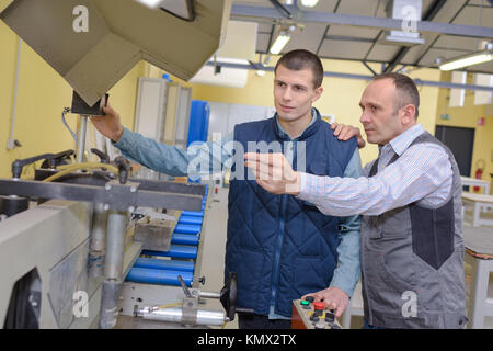 factory manager and engineering apprentice discussing component Stock Photo
