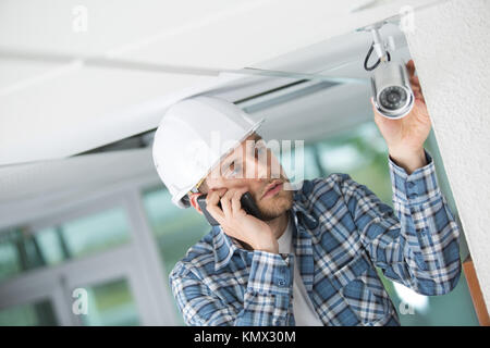 young technician encountering a problem while adjusting cctv camera Stock Photo