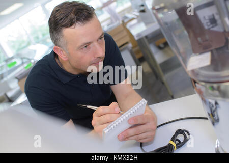 engineer taking notes at control room in factory Stock Photo