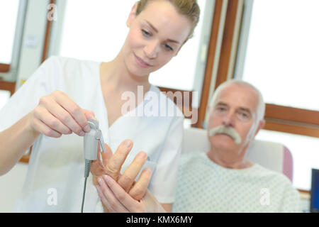 femle nurse fitting oxymeter to senior patient at the hospital Stock Photo