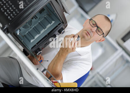 mature male technician repairing oven in kitchen Stock Photo