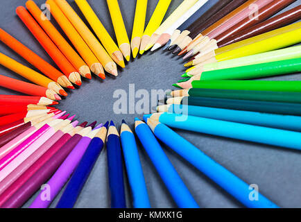 rainbow colorful colored pencil abstract background laying in the shape f a heart on gray background Stock Photo