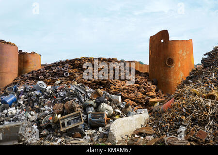 recycling center  with bales of metal and crane with claw tossing truck  and rusty wheels Stock Photo