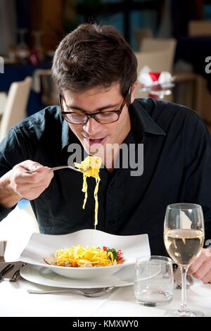Man eating spaghetti with fish and vegetables