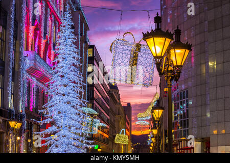 Budapest, Hungary - Beautiful shopping street scene with lamp post, glowing Christmas tree and lights and decorations and colorful sunset sky in centr Stock Photo