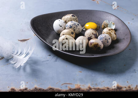 Quail eggs in brown ceramic plate over gray metal surface. Stock Photo