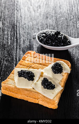 Toast with butter and caviar black wooden background Stock Photo