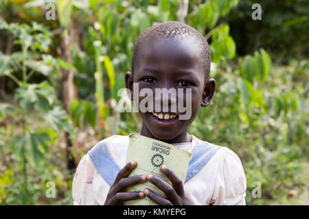 A smiling Ugandan girl holding a notebook. Stock Photo