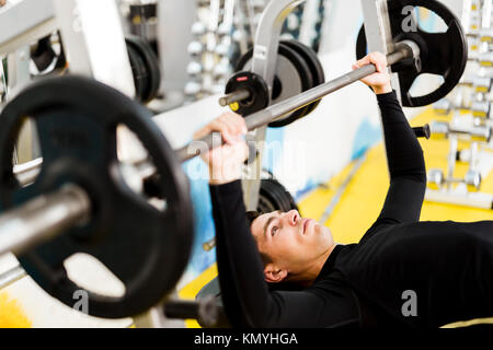 Closeup of young handsome man doing exercises on a bench press Stock Photo
