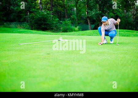 Golf player marking ball on the putting green Stock Photo