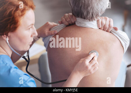 Close up of doctor listening back of patient with stethoscope Stock Photo