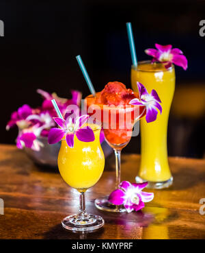 Composition with 3 yellow and red cocktails and orchid flowers on the blurred background Stock Photo