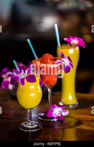 Composition with 3 yellow and red cocktails and orchid flowers on the blurred background Stock Photo