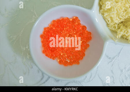 Red caviar in a little bowl on a white background. above view of red dyed salty caviare of halibut fish in glass jar isolated on white background Stock Photo