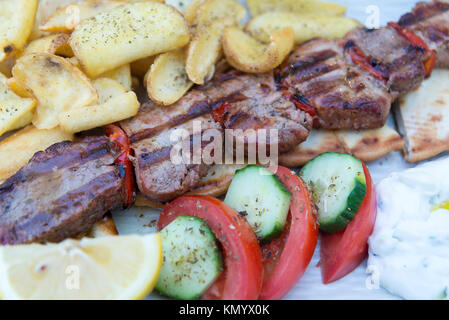 Grilled pork steak in a frying pan, closeup view with fries and vegetables at the restaurant. Stock Photo