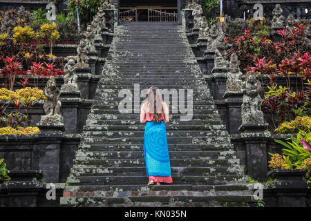 European female tourist poses backward in front of Besakih temple in Bali - Indonesia Stock Photo