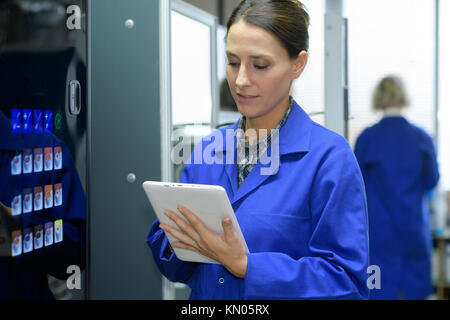 technician holding digital tablet while examining server in server room Stock Photo