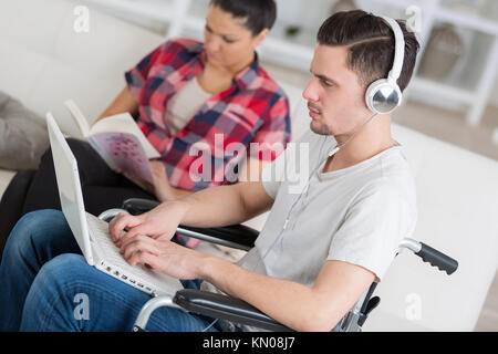 disabled man using laptop sitting next to his girlfriend Stock Photo