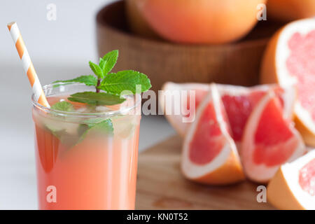 Freshly pressed grapefruit juice with mint leaves and ice on white table close up. Stock Photo
