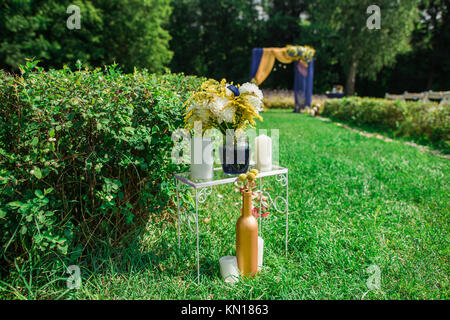 Beautiful settings for outdoors wedding ceremony and celebration. Blurry beautiful arch decorated with yellow and blue fabric in backgroundkground. Ho Stock Photo